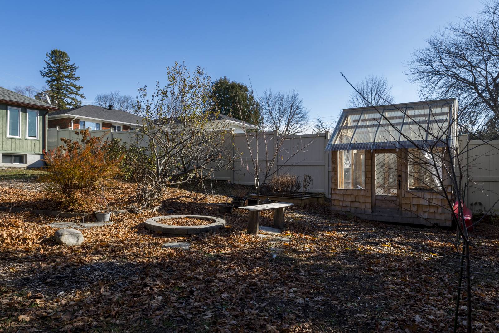 Back yard with a cedar-shake greenhouse, stone fire pit and garden bench