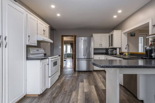 Kitchen: White cabinetry, stainless fridge, pot lights
